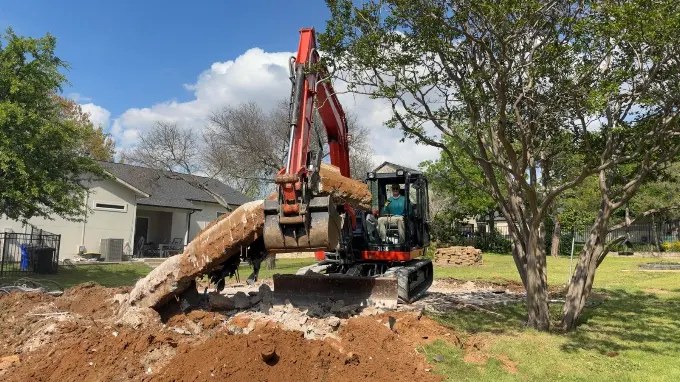 Excavator lifting broken concrete at a Grawe demolition project